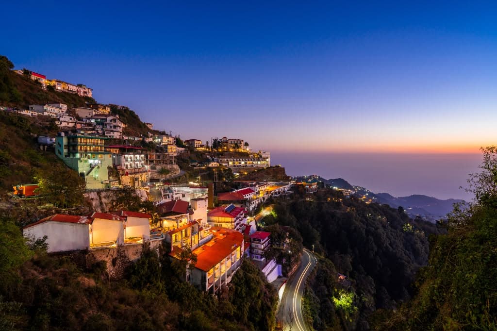 Green Mussoorie valley with wooden cottages and snow peaks